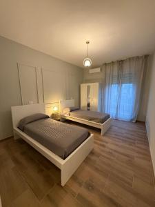 two beds in a large room with wooden floors at Placanica Apartment in Calitri