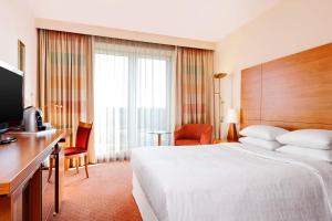 a hotel room with a bed and a desk and a television at Sheraton Duesseldorf Airport Hotel in Düsseldorf