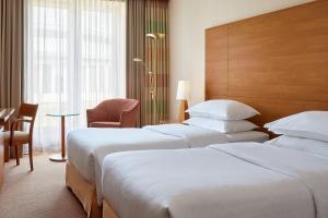 a hotel room with two beds and a table at Sheraton Duesseldorf Airport Hotel in Düsseldorf +47 photos