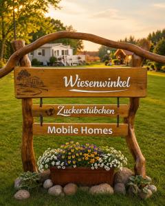 a wooden sign in a yard with flowers at Ferienwohnung-Wiesenwinkel in Kasel-Golzig +3 photos