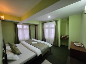 a hotel room with a bed and two windows at Sri Vrindavan Guest House Pure Veg in Darjeeling