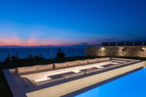 a living room with a couch and a pool at night at Monte Smith Luxury Villas in Rhodes Town