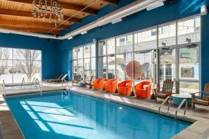 a swimming pool with orange chairs in a building at Aloft by Marriott Green Bay in Green Bay