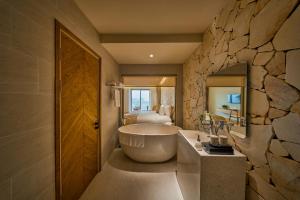 a bathroom with a tub and a stone wall at Olive Hotel Da Lat in Da Lat +120 photos