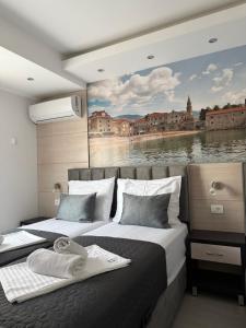 two beds in a room with a painting on the wall at Apartments Vé in Budva