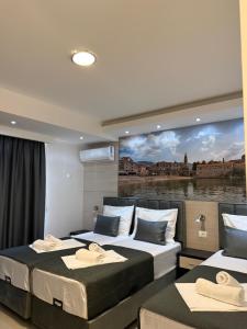 two beds in a room with a painting on the wall at Apartments Vé in Budva