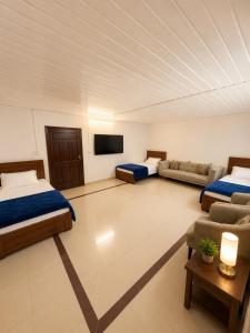a room with two beds and a couch and a tv at Canopy Court Farmhouse Murree in Bhurban