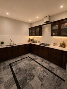 a large kitchen with wooden cabinets and a marble floor at Canopy Court Farmhouse Murree in Bhurban