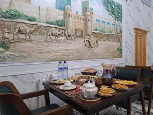 a table with food and a painting on the wall at Sobirjon Guest House in Khiva +14 photos