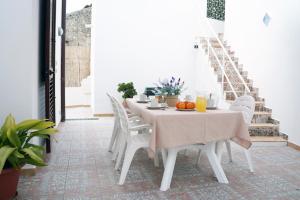 ein weißes Esszimmer mit einem Tisch und weißen Stühlen in der Unterkunft Casa Vacanza da Rosa in Custonaci