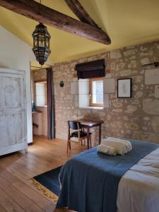 a bedroom with a bed and a table with a chair at Sirona - domaine viticole et chambres d'hôtes in Le Puy-Notre-Dame
