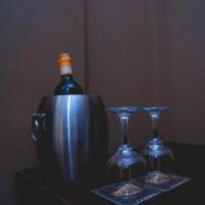 a bottle of wine and two glasses on a table at Golden Quest Hotel in Entebbe
