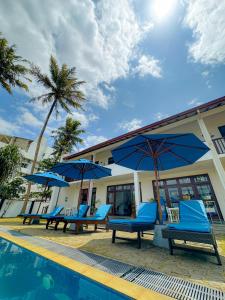 a group of blue chairs and umbrellas next to a pool at Surf Bay Villa Weligama in Pelena