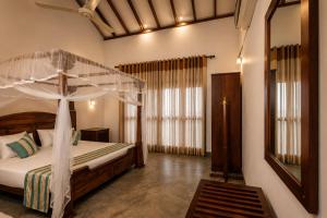 a bedroom with a canopy bed and a mirror at Surf Bay Villa Weligama in Pelena +26 photos