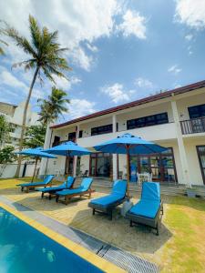 a resort with blue chairs and umbrellas next to a pool at Surf Bay Villa Weligama in Pelena