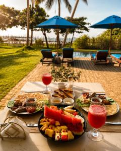 a table topped with plates of food and drinks at Surf Bay Villa Weligama in Pelena