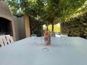 a bottle of wine sitting on a table with two wine glasses at Locations proche de la plage de Barcaggio accessible par une piste en terre de 3,5 kilometres de Tizzano en voiture in Sartène +5 photos