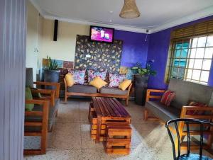 a living room with a couch and a tv at Golden Quest Hotel in Entebbe +9 photos
