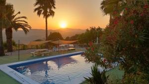 a swimming pool with a sunset in the background at Casita Zagra in La Carrera de la Viña