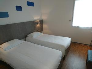 two beds in a hotel room with a window at H24 HOTEL in Le Mans