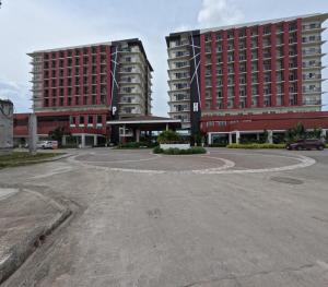 an empty parking lot in front of two tall buildings at Cozy 1BR Prime World District, Near Airport, Gaisano Grand Mall, Mactan Doctor's Hospital in Agus