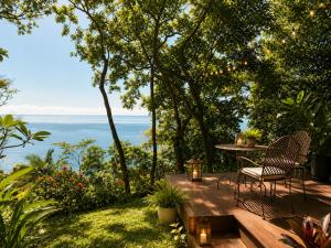 a patio with a table and chairs and the ocean at Gunnadoo Holiday Hut with Ocean Views and Jacuzzi in Miallo