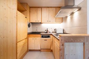 a kitchen with wooden cabinets and a stove top oven at Dolomitihouse NOGHERA in Fiera di Primiero