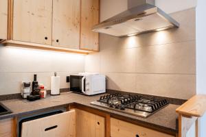 a kitchen with a stove and a microwave at Dolomitihouse NOGHERA in Fiera di Primiero