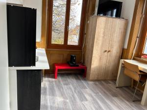 a room with a tv and a red stool at Studio in Tramelan