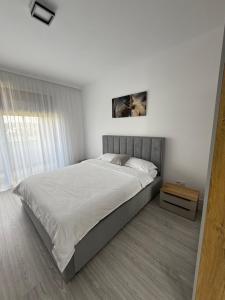 a white bedroom with a large bed and a table at Malvina Apartments Cazare Mures in Târgu-Mureş