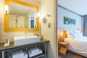 a bathroom with a sink, mirror, and bathtub at Hotel Le Morgane in Chamonix
