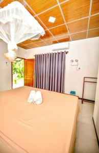 a bedroom with a bed with two white towels on it at Pinnacle Safari Resort in Udawalawe