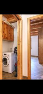 a laundry room with a washing machine and wooden cabinets at Baita PUPILLE in Osteria Alpina