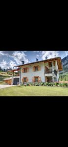 a large white building with windows and a grass field at Baita PUPILLE in Osteria Alpina