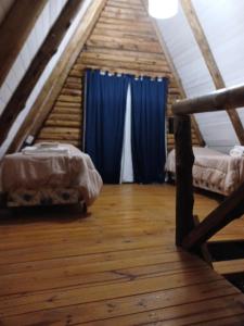 a attic room with two beds and a blue curtain at Complejo del Canton Valais in Baradero