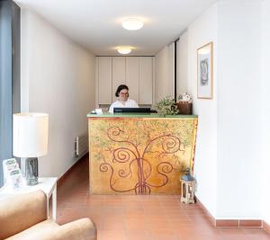 a woman sitting at a counter in a room at Tailormade Hotel AL GIARDINETTO Biasca in Biasca