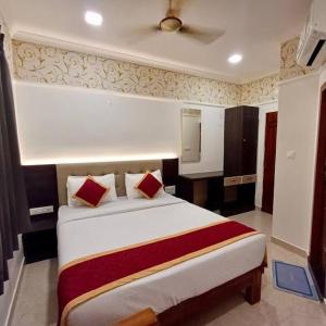 a bedroom with a large white bed with red pillows at Hotel Town Palace in Shimoga