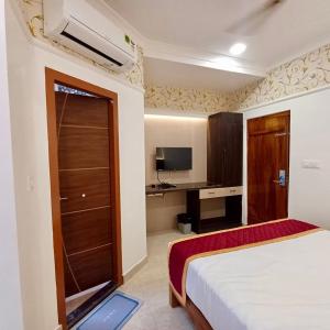 a hotel room with a bed and a television at Hotel Town Palace in Shimoga