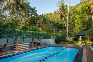 a swimming pool in a resort with a hill in the background at Nature Trails Boutique Hotel in Unawatuna