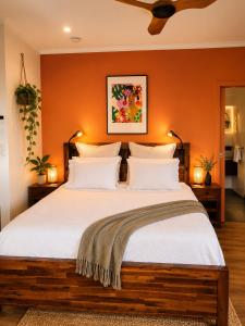 a bedroom with a large bed with an orange wall at Sky: rainforest and ocean views with jacuzzi in Miallo