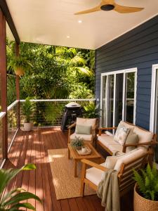 a screened porch with a couch and chairs on a deck at Sky: rainforest and ocean views with jacuzzi in Miallo