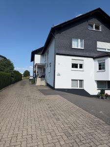 a house with a brick driveway next to a building at Timos Ferienwohnung in Schmallenberg