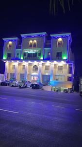a lit up building with cars parked in front of it at شقق برج نوران للشقق المخدومة Nouran Tower Serviced Apartments in Al Khobar