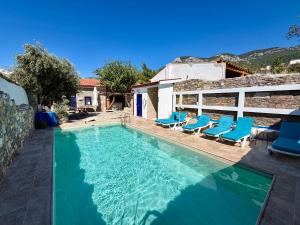 a swimming pool with blue chairs and a house at Bahab Guest House in Doğanbey