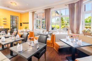 a restaurant with tables and chairs and windows at Hotel Novum in Hinte