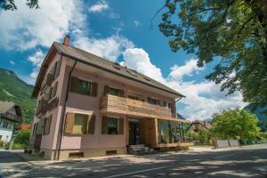 ein rosafarbenes Haus mit Fenstern auf einer Straße in der Unterkunft Apartments and Rooms Skok in Bovec