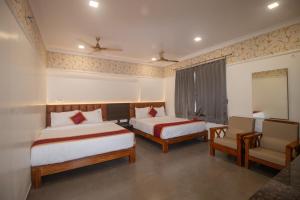a hotel room with two beds and a chair at Hotel Town Palace in Shimoga