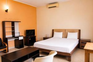a bedroom with a bed and a desk and a tv at Chambre à louer in Moroni