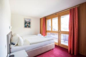 a bedroom with a bed and a large window at Aparthotel Ambassador in Bellwald +23 photos