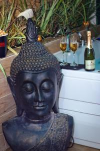 a statue of a buddha with two glasses of wine at JADE Hammam & Jacuzzi in Brie-Comte-Robert
